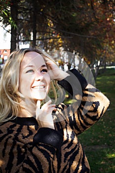 Portrait of a beautiful young woman enjoying autumn in the park. Attractive blonde in autumn park on a background of