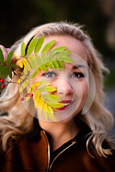 Portrait of a beautiful young woman enjoying autumn in the park. Attractive blonde in autumn park on a background of