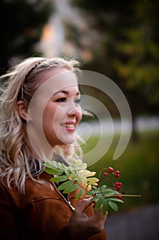 Portrait of a beautiful young woman enjoying autumn in the park. Attractive blonde in autumn park on a background of