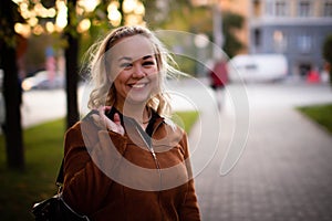 Portrait of a beautiful young woman enjoying autumn in the park. Attractive blonde in autumn park on a background of