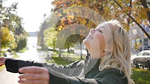 Portrait of a beautiful young woman enjoying autumn in the park. Attractive blonde in autumn park on a background of