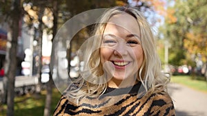 Portrait of a beautiful young woman enjoying autumn in the park. Attractive blonde in autumn park on a background of