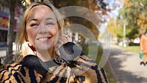 Portrait of a beautiful young woman enjoying autumn in the park. Attractive blonde in autumn park on a background of