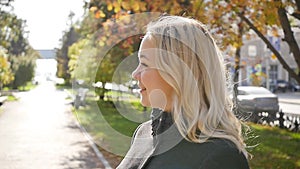 Portrait of a beautiful young woman enjoying autumn in the park. Attractive blonde in autumn park on a background of