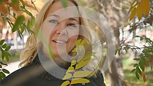 Portrait of a beautiful young woman enjoying autumn in the park. Attractive blonde in autumn park on a background of