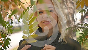 Portrait of a beautiful young woman enjoying autumn in the park. Attractive blonde in autumn park on a background of