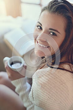 Weekends are all about taking it easy. Portrait of a beautiful young woman enjoying a cup of coffee at home.