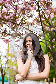 Portrait of beautiful young woman enjoying sunny day in park during cherry blossom season on a nice spring day