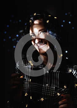 Portrait of a beautiful young woman with fairy lights with a shadow pattern on the face and body