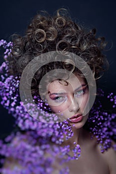 Portrait of beautiful young woman with fancy hairdo and violet flowers around her face, soft focus, grainy