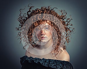 Portrait of beautiful young woman with flying curly hair