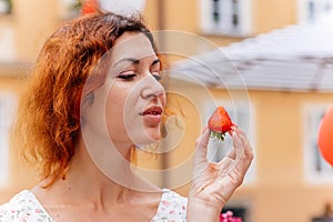 Portrait of the beautiful young woman with fresh red strawberries. Girl enjoy eating appetizing and juicy strawberry