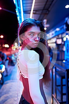 Portrait of a beautiful young woman with glasses in futuristic neon light