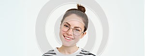 Portrait of beautiful young woman in glasses, wearing eyewear, smiling and looking happy, trying on new spectacles