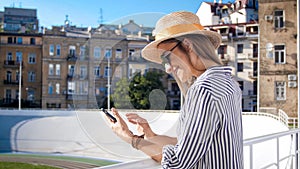 Portrait of beautiful young woman in hat using mobile phone on stadium at hot summer day