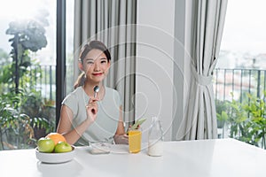 Portrait of beautiful young woman having breakfast in the kitchen