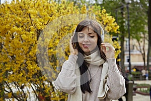 Portrait of beautiful young woman in headphones listening to music outdoor. Casual lifestyle, audio healing, learning -