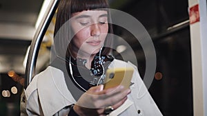 Portrait of beautiful young woman in headphones riding in public transport, listen music and browsing on yellow