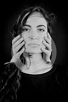 Portrait of a beautiful young woman with her cheeks covered with hands - concept of worries, fears and anxiety