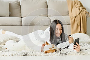 Portrait of beautiful young woman with her dog using mobile phone at home