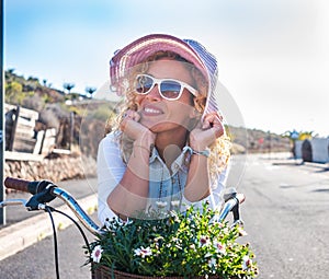Portrait of a beautiful young woman, hippie style, enjoying bicycle outdoor under the sunlight. Palm trees and cactus around her.