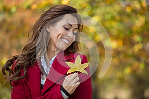 Portrait of a beautiful young woman holding an autumn leaf and s