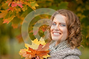 Portrait of beautiful young woman holding autumn leaves