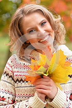 Portrait of beautiful young woman holding autumn leaves