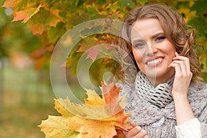 Portrait of beautiful young woman holding autumn leaves