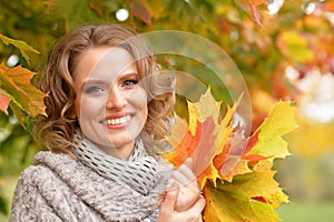 Portrait of beautiful young woman holding autumn leaves