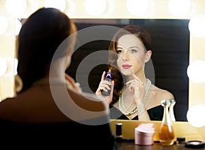 Portrait of beautiful young woman holding bottle of perfume and