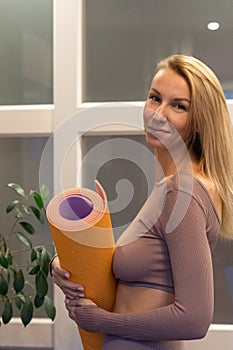 Portrait of beautiful young woman holding colorful mat for sports. Sport and healthy lifestyles concept