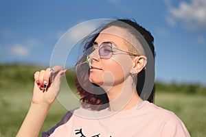 Portrait of beautiful young woman holding and smelling little chamomile flower