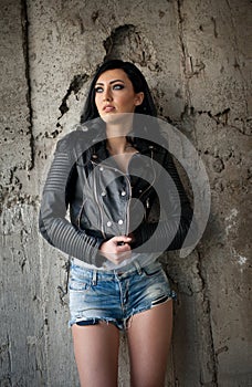 Portrait of beautiful young woman with jeans,white undershirt black leather jacket , in urban background.