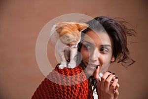 Portrait of the beautiful young woman with a kitten on the shoulder. Concept of loving animals, taking care and having fun with