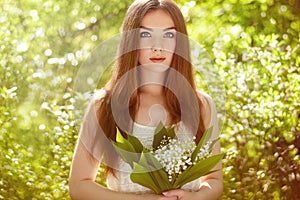 Portrait of beautiful young woman with lily of the valley