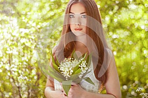 Portrait of beautiful young woman with lily of the valley