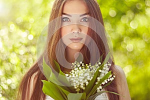 Portrait of beautiful young woman with lily of the valley
