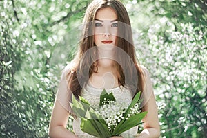 Portrait of beautiful young woman with lily of the valley