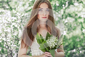 Portrait of beautiful young woman with lily of the valley