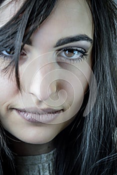 Portrait of a beautiful young woman with long brown hair with a bewitching look who smiles slightly