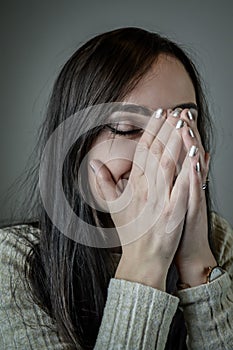 Portrait of a beautiful young woman with long brown hair covering her mouth as she bursts out laughing