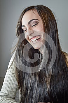 Portrait of a beautiful young woman with long brown hair laughing happily