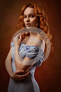 Portrait of a beautiful young woman with long curly red hair, dressed in a fashionable light light blue dress