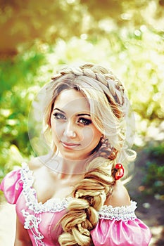 Portrait of a beautiful young woman with long hair braided in braid on the background nature.