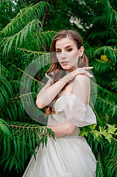 portrait. beautiful woman with light eyes in white dress against of green leaves