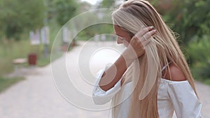 Portrait of a beautiful young woman with long hair over park background, wearing natural makeup