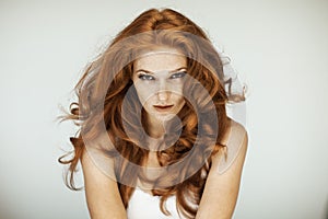 Portrait of a beautiful young woman with long red curly hair and freckles