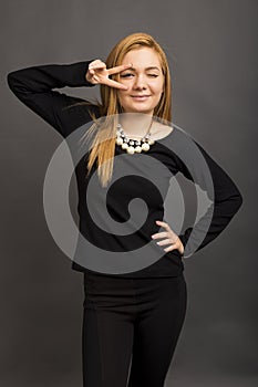 Portrait of beautiful young woman looking through peace sign a