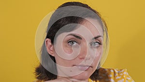 Portrait of a beautiful young woman looking thoughtfully at the camera. Static emotions of a woman on a yellow